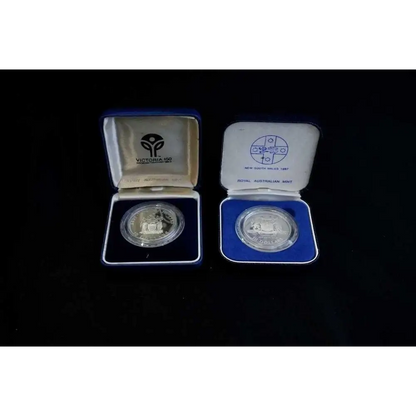 Two silver coins in open display cases on a black background
