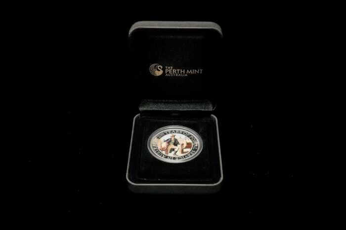 A Perth Mint Australia commemorative coin presented in an open black gift box on a black background. The circular silver-toned coin features a central figure and is displayed inside a black velvet-lined box with the Perth Mint logo visible on the inside lid.