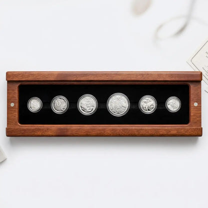 A six-piece silver coin collection displayed inside a rectangular wooden case with a black velvet interior, set against a clean white background.