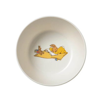 An off-white ceramic bowl featuring a colorful illustration of two cartoon rabbits on a yellow blanket inside the bowl.