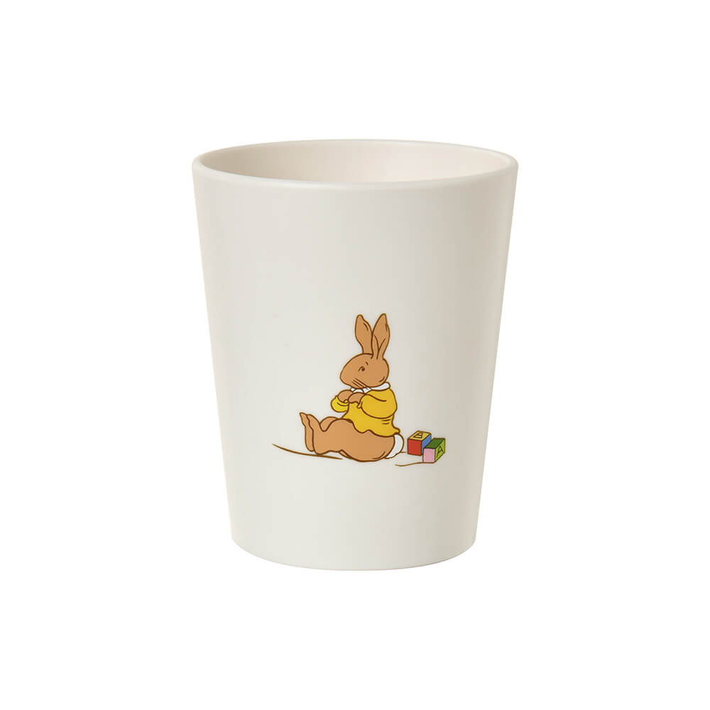 An off-white ceramic cup featuring a cartoon illustration of a brown rabbit wearing a yellow sweater sitting next to colorful blocks.