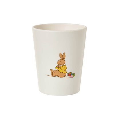An off-white ceramic cup featuring a cartoon illustration of a brown rabbit wearing a yellow sweater sitting next to colorful blocks.