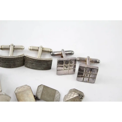Collection of silver cufflinks on a white background