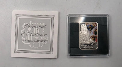 A silver-colored religious medal from the Principat d'Andorra, dated 1911-1939, displayed next to its white presentation card on a gray background.
