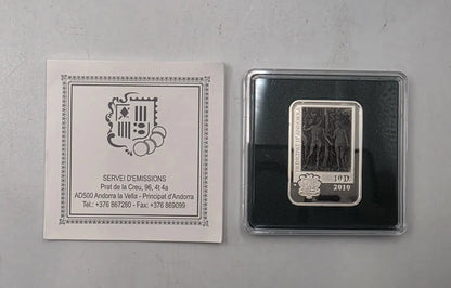 A 10 dimes 2010 silver coin from Andorra, displayed next to its original white paper certificate insert on a light gray surface.