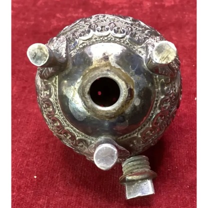 Decorative metal object with intricate designs on a red background