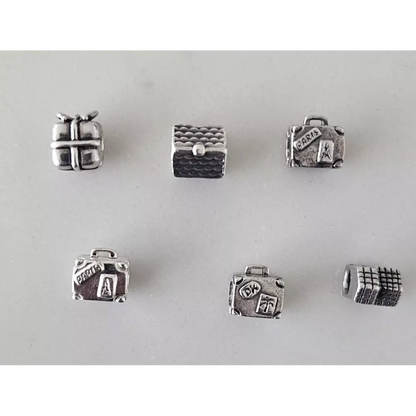 Set of silver jewelry charms shaped like a suitcase, gift box, and other items