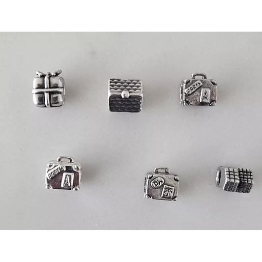 Set of silver jewelry charms shaped like a suitcase, gift box, and other items