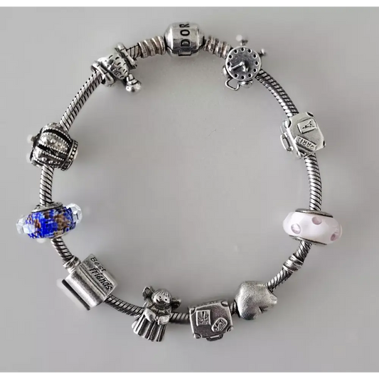 Silver charm bracelet with various charms on a gray background
