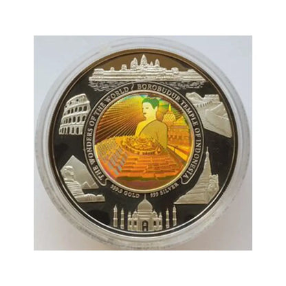 A round commemorative coin featuring Borobudur Temple in Indonesia, displayed inside a clear protective plastic capsule. The coin has a black background with silver-toned borders and a central gold-toned illustration of Buddha, surrounded by silhouettes of other famous landmarks including the Colosseum, Taj Mahal, and the Eiffel Tower.