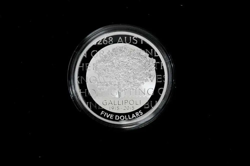 A circular silver coin with a clear protective plastic capsule, featuring the text 'GALLIPOLI 2015-2026 FIVE DOLLARS' and a textured central design, set against a solid black background.