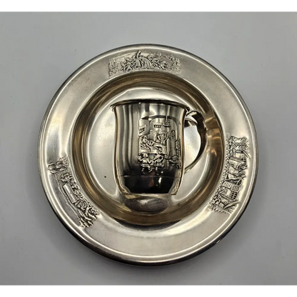 Silver cup and saucer with intricate designs on a gray background