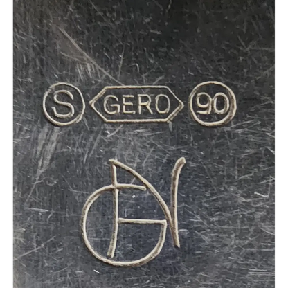 Close-up of engraved marks on a metallic surface, including 'S', 'GERO 90', and a signature.