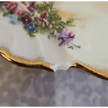Decorative ceramic plate with floral design and gold rim on a textured surface