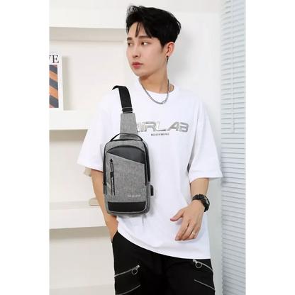 Person wearing a white t-shirt with a brand logo and carrying a gray crossbody bag.