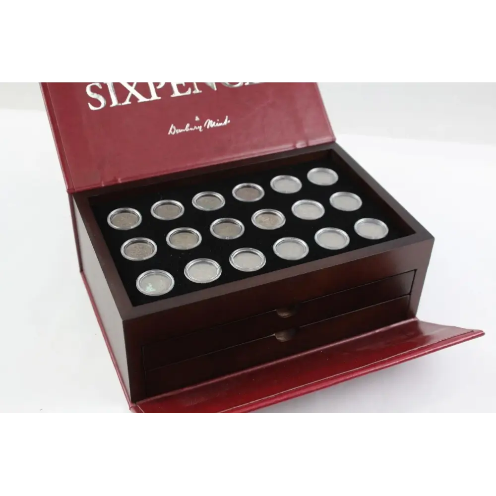Collection of silver coins in a wooden display box with 'Sixpence' branding.