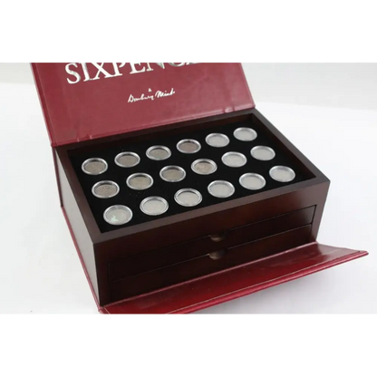 Collection of silver coins in a wooden display box with 'Sixpence' branding.