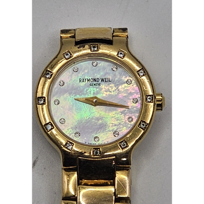 Gold watch with a decorative face on a gray background