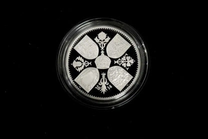 A round silver coin with a detailed traditional design, encased in a clear protective plastic capsule, set against a solid black background.