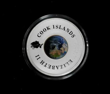 A round silver Cook Islands coin in a clear protective capsule, featuring a central globe design and the text 'COOK ISLANDS' and 'ELIZABETH II' on a black background.