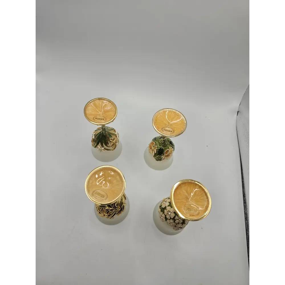 Five small decorative items with gold accents on a gray surface