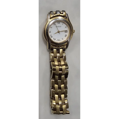 Gold watch with a white face on a gray background