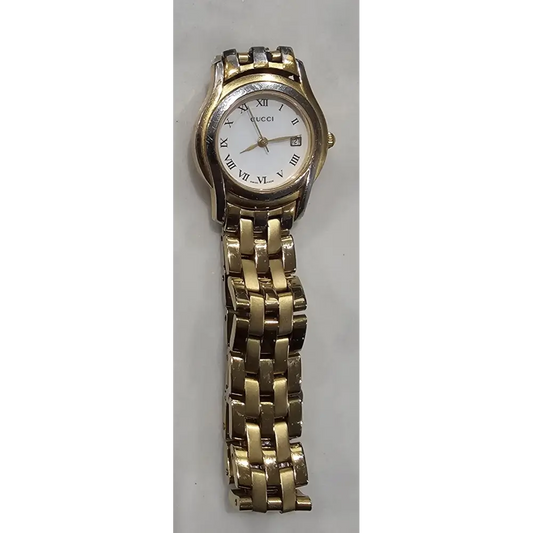 Gold watch with a white face on a gray background