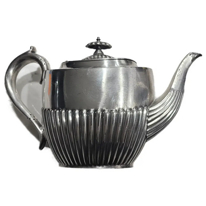 Silver teapot with ribbed design on a white background