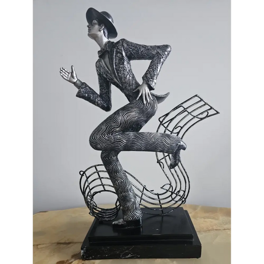 Statue of a dancer with a hat on a music note-shaped