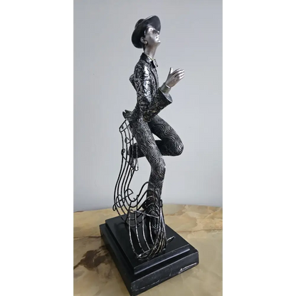 Statue of a person in a suit and hat on a wooden surface with a gray background