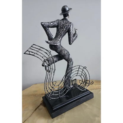 Decorative sculpture of a dancer with musical notes on a plain background