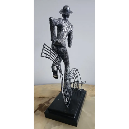 Metallic sculpture of a figure with a hat and musical instruments 