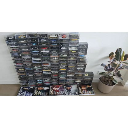 Stack of toy car boxes with a plant on a white background