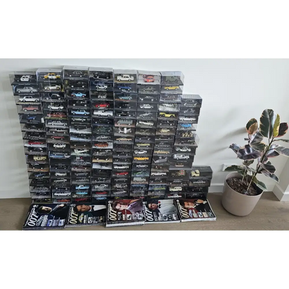 Stack of model car boxes with magazines on a white surface