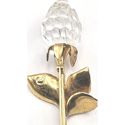 Gold rose brooch with a clear crystal on a white background