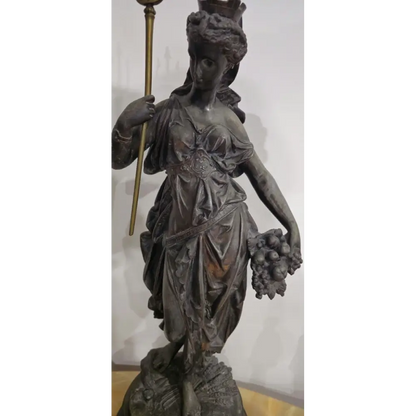 Bronze statue of a woman holding a staff and basket