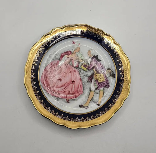 Decorative plate with a gold rim featuring a scene of a man and woman
