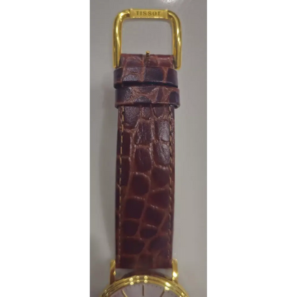 Brown crocodile-patterned leather strap with gold hardware on a gray background