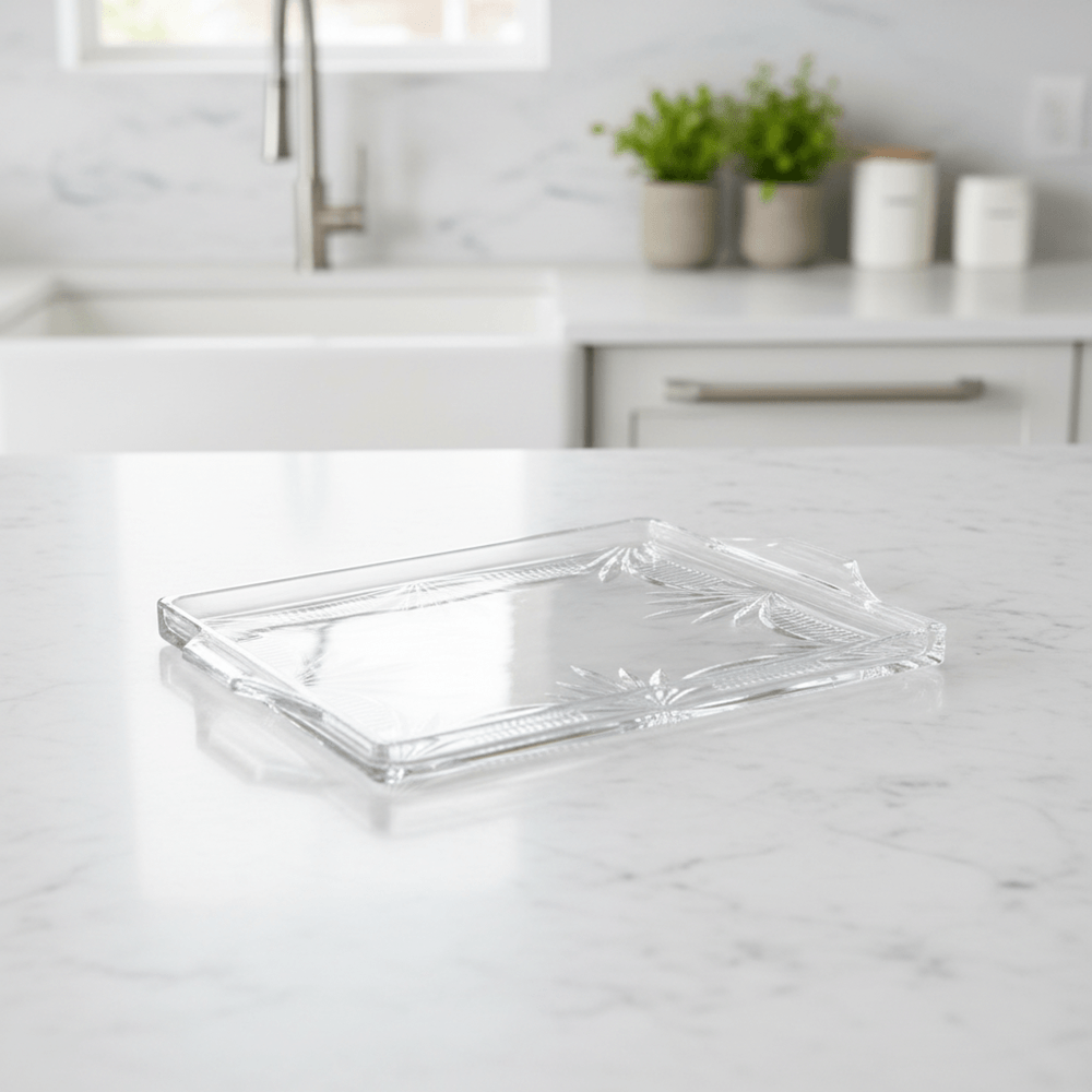 Clear glass tray on a marble kitchen counter with plants in the background