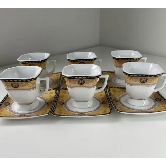 Set of six white ceramic cups and saucers with gold and black patterns