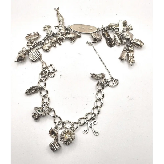 Silver charm bracelet with various charms on a white background