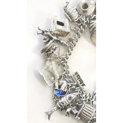 Silver charm bracelet with various charms on a white background