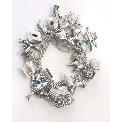 Silver charm bracelet with various charms on a white background