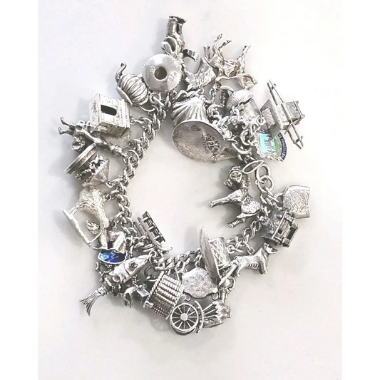 Silver charm bracelet with various charms on a white background