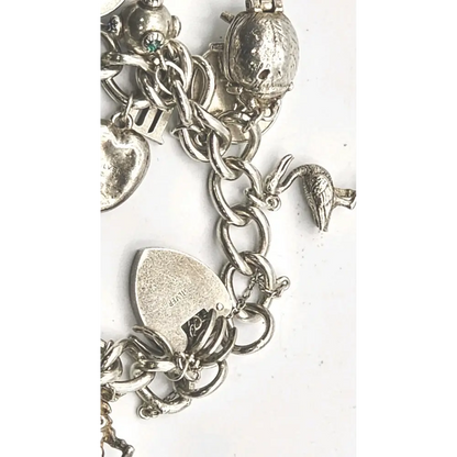 Silver charm bracelet with various charms on a white background