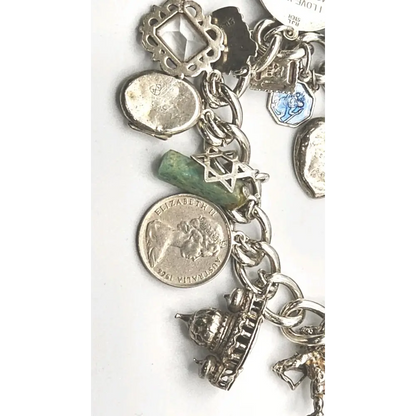 Silver charm bracelet with various charms on a white background
