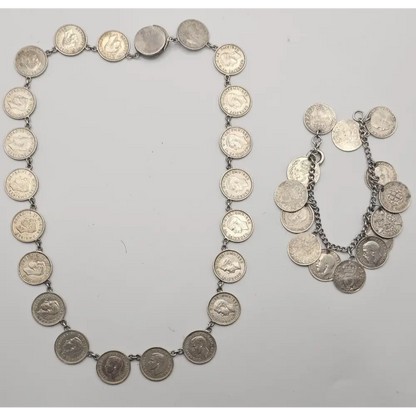 Silver coin necklace and bracelet on a light gray background