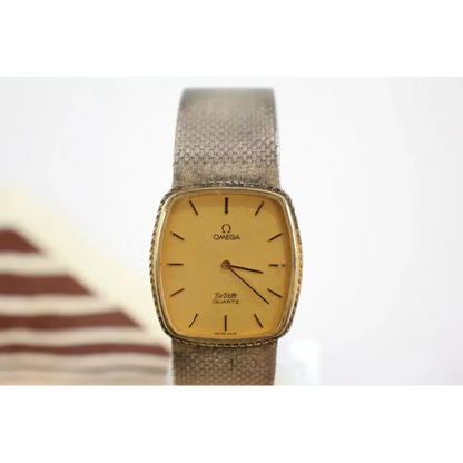 Vintage Omega watch with gold face and brown strap on a white background