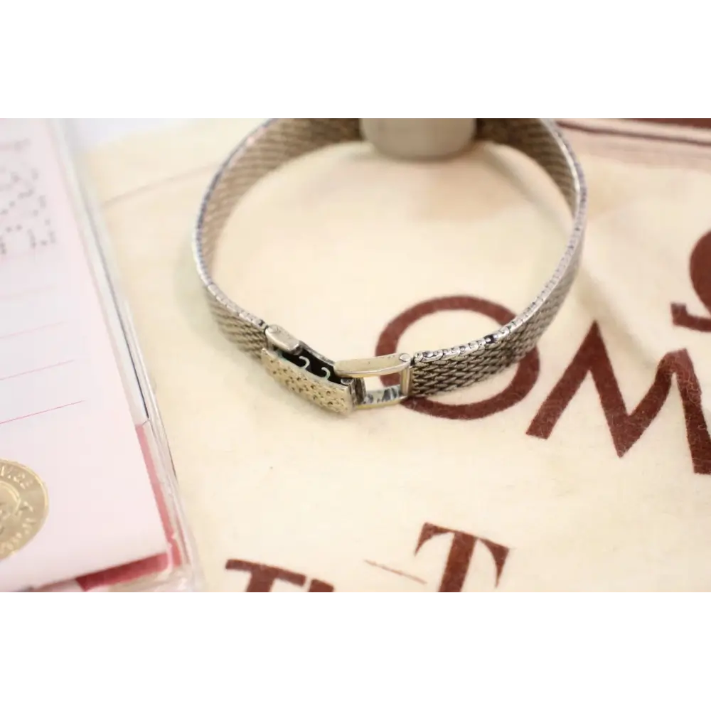 Silver bracelet on a textured surface with visible brand name