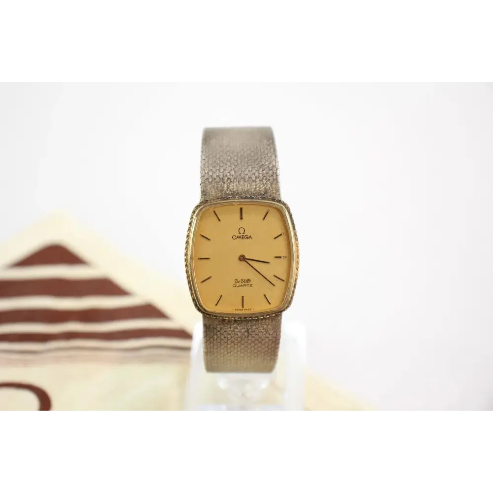 Vintage Omega watch with beige face and brown strap on a white background